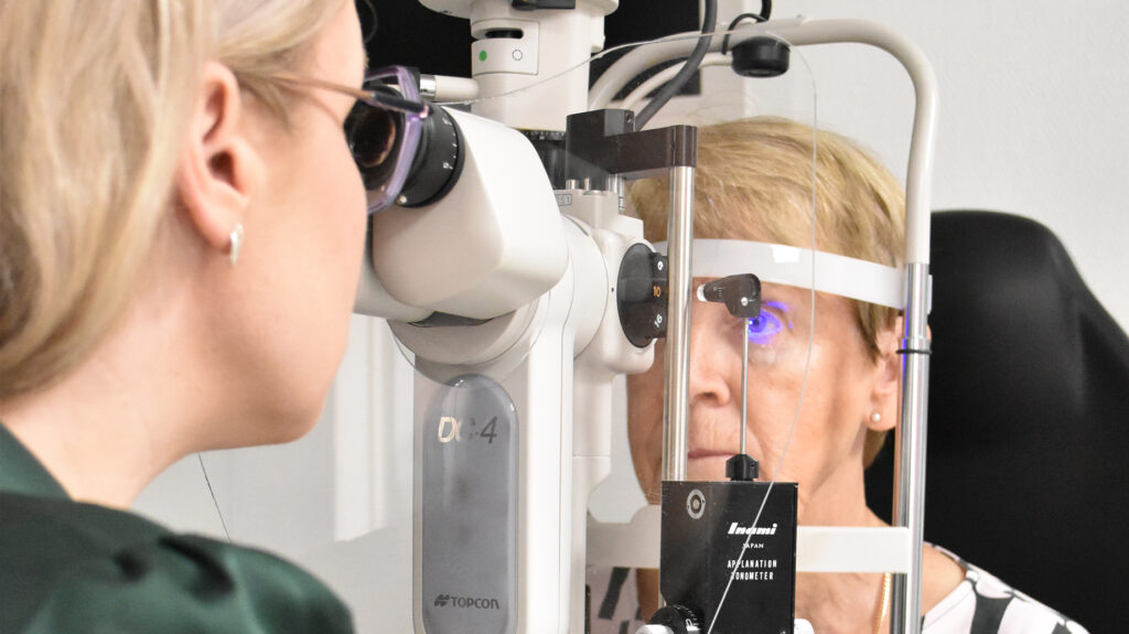 Optometristi tutkii asiakkaan silmän pintaa mikroskoopilla Uudessa-Optiikassa.