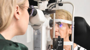 Optometristi tutkii asiakkaan silmän pintaa mikroskoopilla Uudessa-Optiikassa.